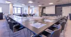 Konferencelokale med borde i u-form, tavler og lysindfald fra vindue