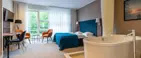 En juniorsuite med badekar og grøn skov udenfor vinduet