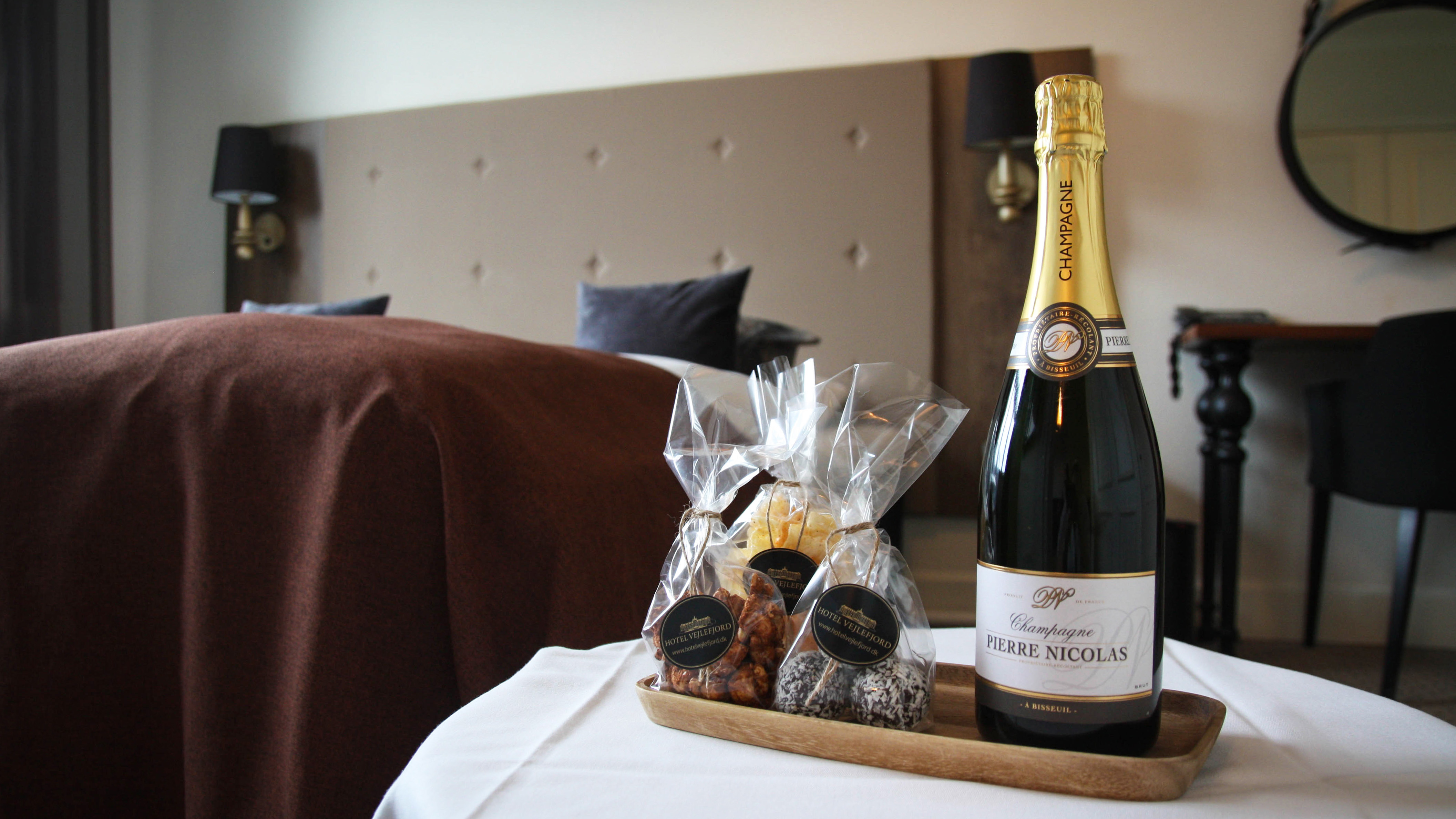 En velkomstpakke med champagne og snacks står klar på et hotelværelse