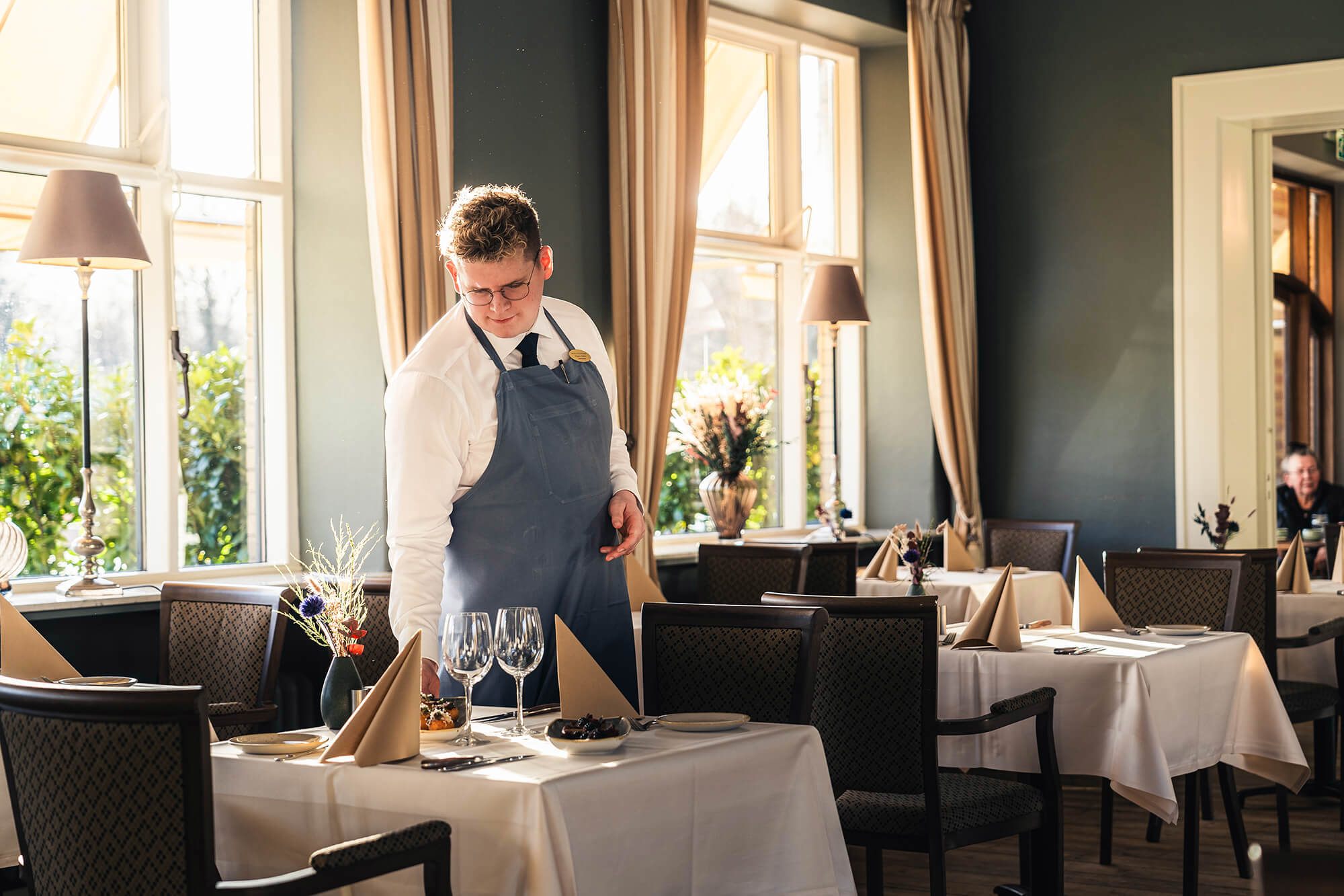 En tjener dækker borde i en hyggelig restaurant