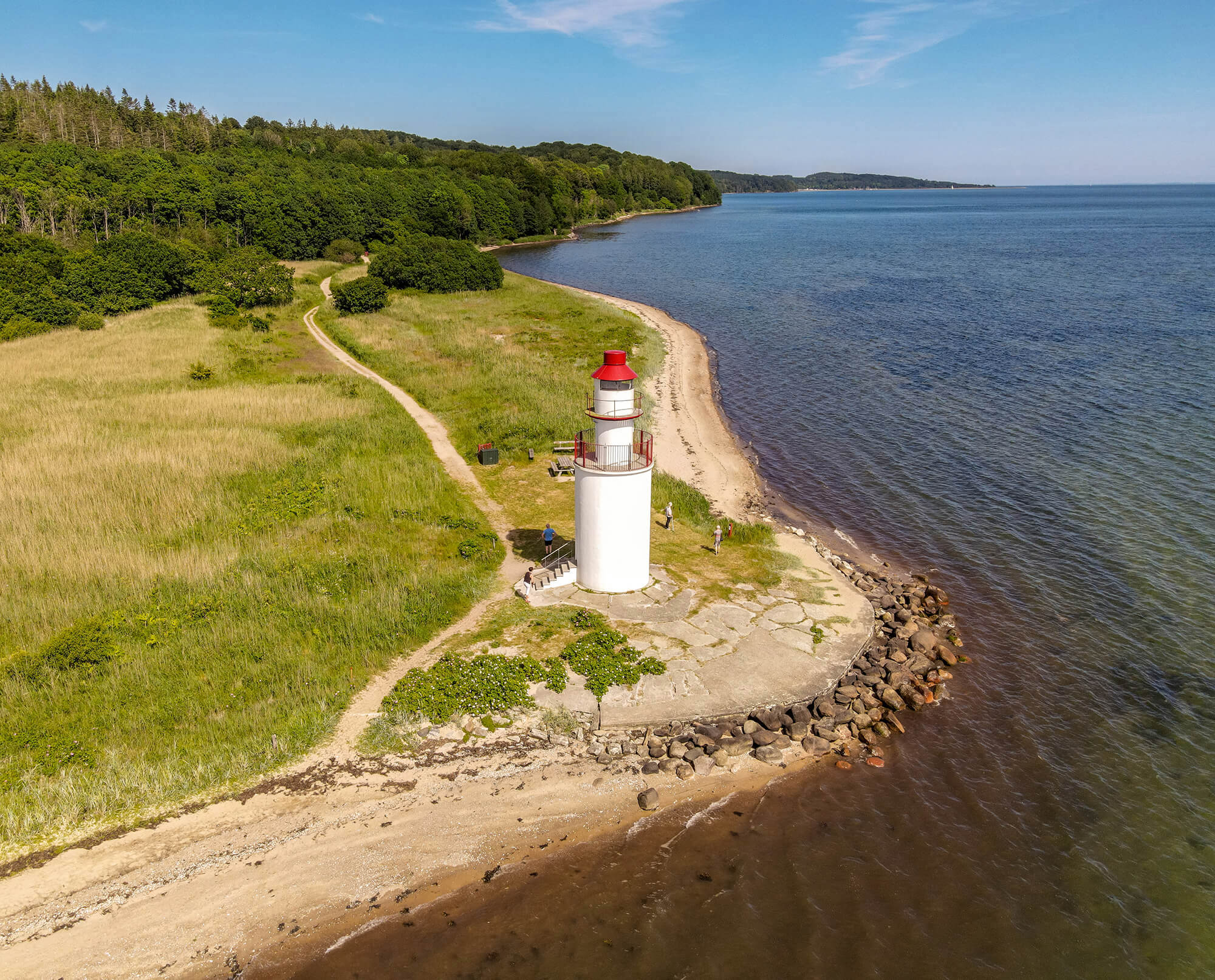 Træskohage fyrtårn står på en pynt ved Vejle Fjord, som på billedet er blå og skoven grøn
