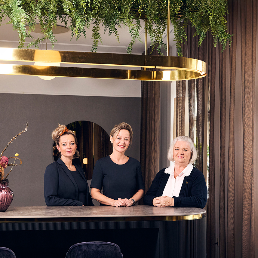 Tre smilende kvinder i Hotel Vejlefjords uniformer fra konferenceafdelingen