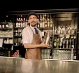 Bartender som står med en shaker ved en bardisk